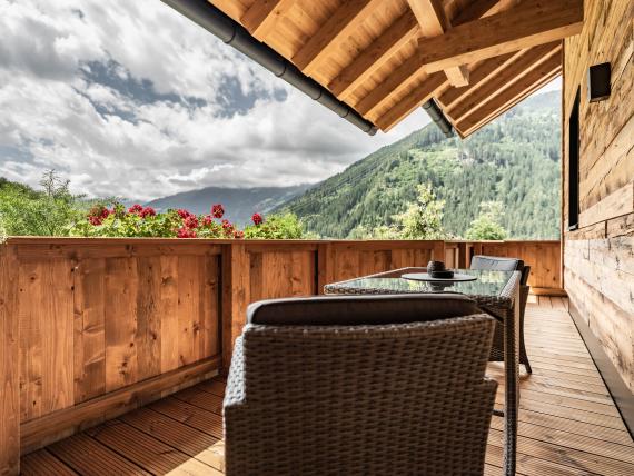 Balkon am Hochfeldhof mit Holzverkleidung, Tisch, Stühlen und Bergblick