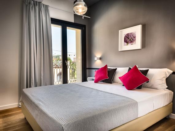 Teku Boutique Hotel: camera matrimoniale moderna con balcone, letto bianco e cuscini rossi