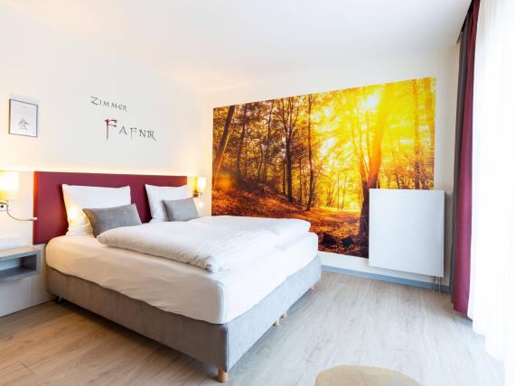 Modernes Doppelzimmer im Mythenresort Heimdall mit Wald-Wandbild und großem Fenster