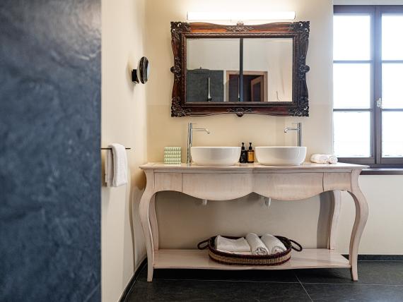 Badezimmer mit Doppelwaschbecken und antikem Spiegel im Castel Sallegg