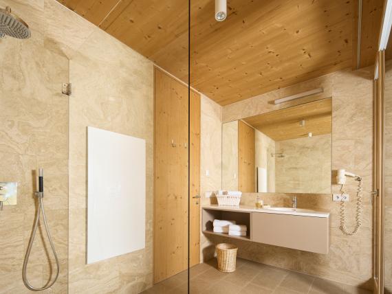 Hochfeldhof Badezimmer mit beiger Marmorwand, Holzdecke und moderner Dusche