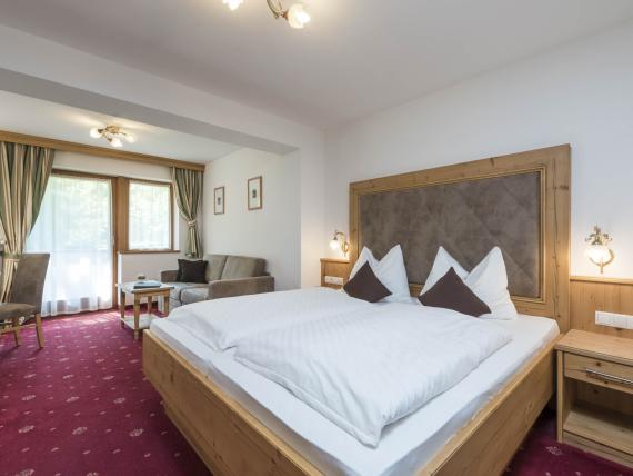 Zimmer im Hotel Waldsee mit Doppelbett, Sitzbereich und roten Teppich