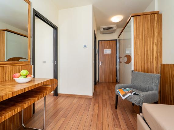 Area moderna della camera d'hotel al Bibione Palace Hotel con pavimento in legno e poltrona