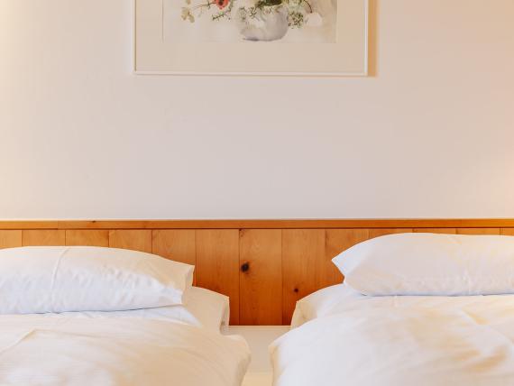 Zwei Einzelbetten im Hotel Aurora mit Holzverkleidung und weißer Bettwäsche