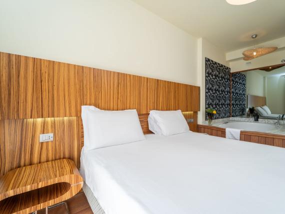 Camera doppia moderna al Bibione Palace Hotel con testiera in legno e grande specchio