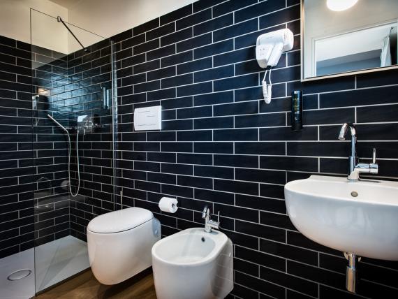 Bagno del Teku Boutique Hotel con piastrelle nere, doccia, WC e lavabo