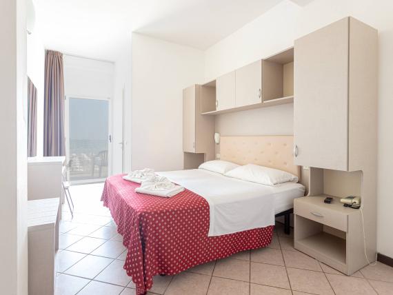 Camera luminosa con letto e copriletto rosso a fiori