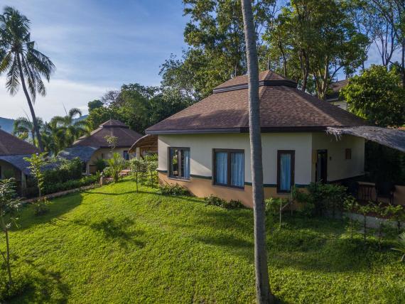 The Mangosteen Ayurveda & Wellness Resort cottages surrounded by greenery and palm trees