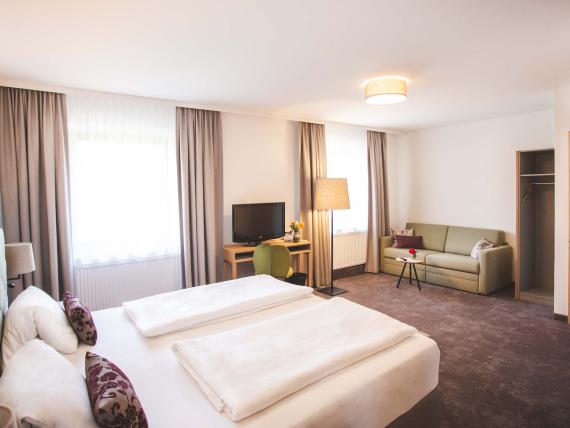 Der Dolomitenhof ***S komfortables Hotelzimmer mit Doppelbett und Sofa