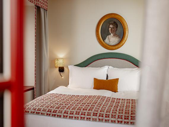 Gemütliches Zimmer mit Bett und Portrait an der Wand im Castel Sallegg