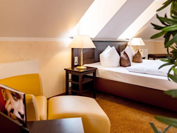 Gemütliches Zimmer mit Sessel und Bett im Burghotel Staufeneck