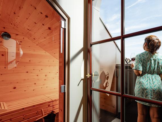 Person mit Glas Wein auf Balkon neben Sauna im Castel Sallegg