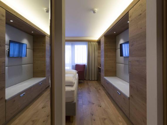 Hotel Panorama Zimmer mit Holzeinrichtung, Bett, Fernseher und Fenster