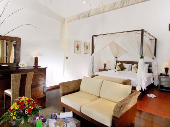 The Mangosteen Ayurveda & Wellness Resort room with canopy bed and cozy seating area