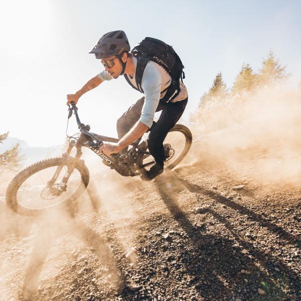 Mountain biker riding dusty trail downhill at Excelsior Dolomites Life Resort