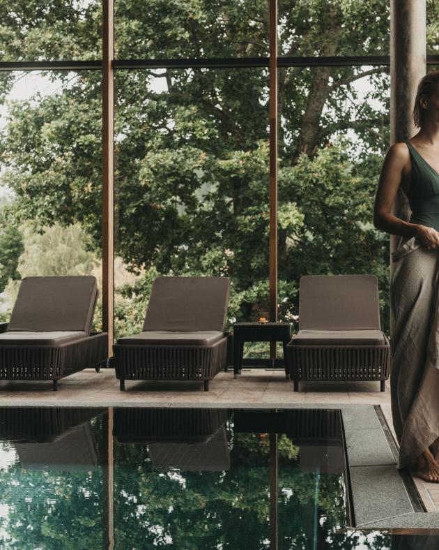 Frau am Pool mit Blick auf Bäume im Eibl-Brunner Spa-Bereich