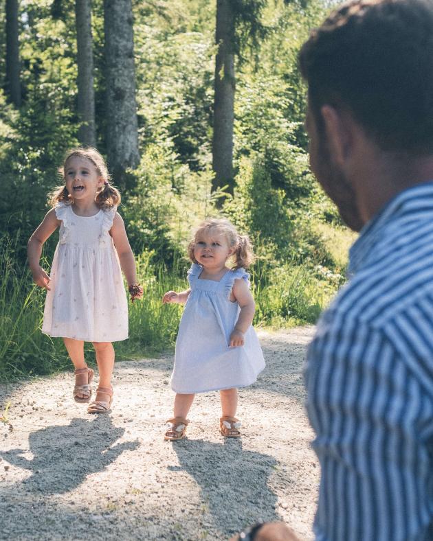 Eibl-Brunner Frau im weiten Grasfeld mit weißen Kleidern im Sonnenlicht