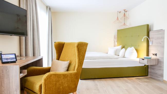 Modernes Zimmer mit gelbem Sessel im Pfalzblick Wald Spa Resort