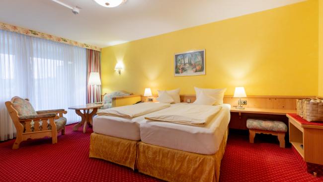 Gemütliches Doppelzimmer im Pfalzblick Wald Spa Resort mit Sitzbereich und gelben Wänden