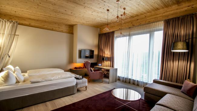 Modernes Zimmer im Pfalzblick Wald Spa Resort mit Bett und gemütlichem Sessel