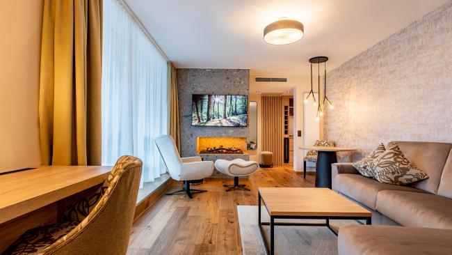 Modernes Wohnzimmer im Pfalzblick Wald Spa Resort mit Kamin und gemütlicher Einrichtung