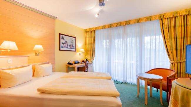 Hell eingerichtetes Doppelzimmer im Pfalzblick Wald Spa Resort mit großem Fenster