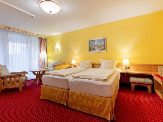 Gemütliches Doppelzimmer im Pfalzblick Wald Spa Resort mit Sitzbereich und gelben Wänden