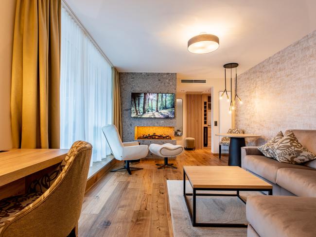 Modernes Wohnzimmer im Pfalzblick Wald Spa Resort mit Kamin und gemütlicher Einrichtung