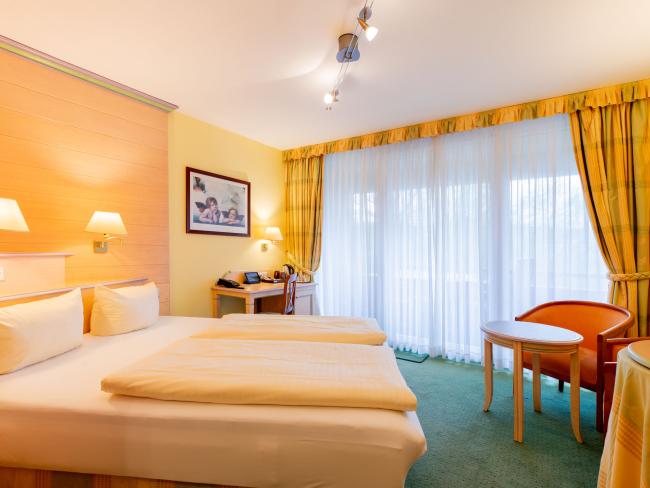 Hell eingerichtetes Doppelzimmer im Pfalzblick Wald Spa Resort mit großem Fenster