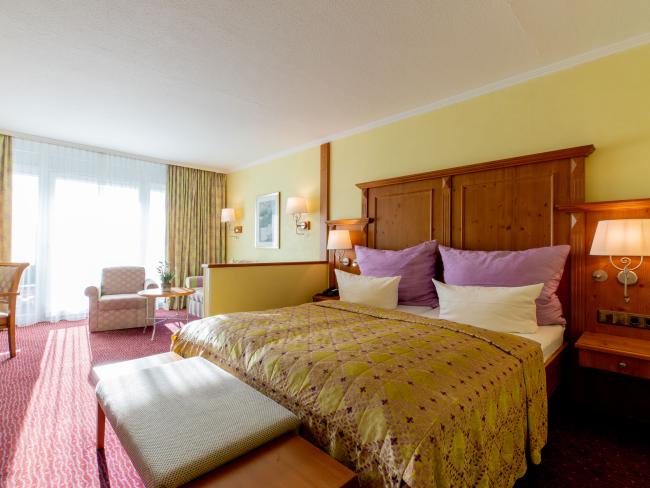 Komfortables Zimmer im Pfalzblick Wald Spa Resort mit großem Bett und Sitzbereich