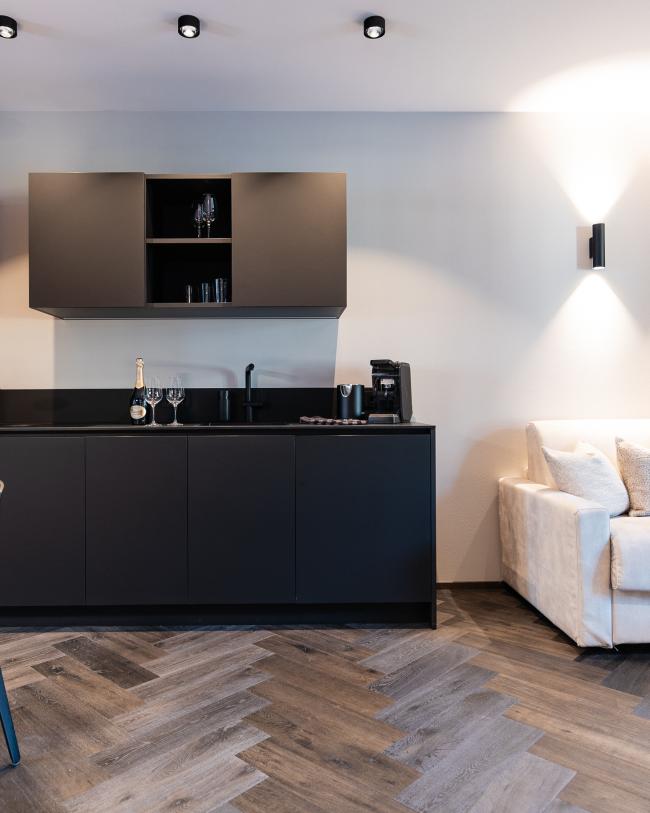 Interno moderno con cucina nera e divano bianco nello stile Schwarzer Adler