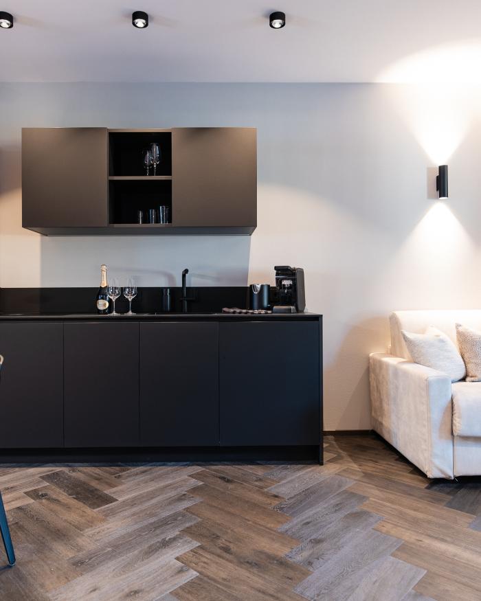 Moderner Wohnraum mit schwarzer Küche und weißem Sofa im Schwarzer Adler Stil