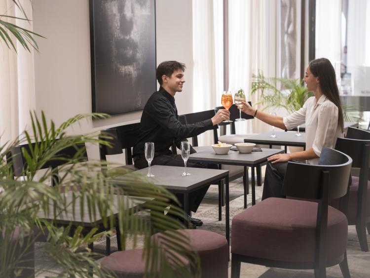 Guests toast with drinks in the modern lounge area of Hotel Touring Verona