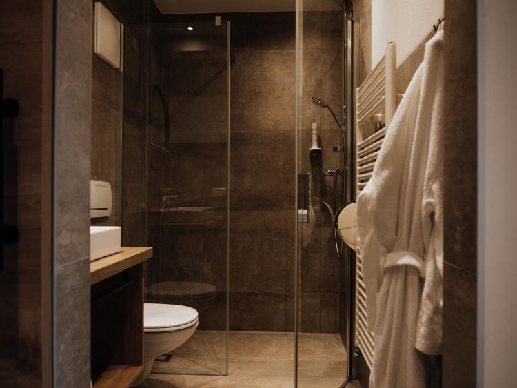 Bad im Hotel Forstauerwirt mit Walk-in-Dusche, Waschbecken, WC und Bademänteln