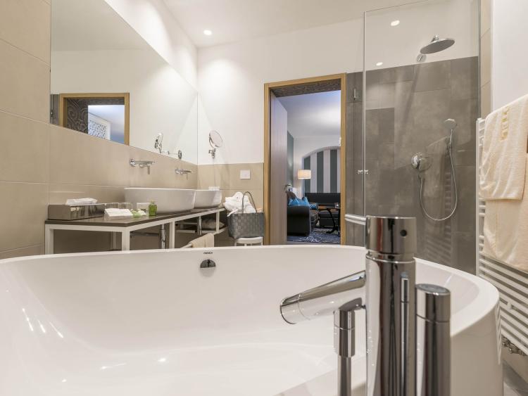 Modernes Badezimmer mit Badewanne, Dusche und Handtuchhalter.