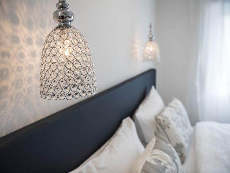 Stilvolles Schlafzimmer mit Pendelleuchten und dekorativen Kissen.