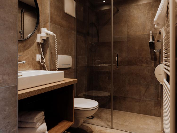 Badezimmer im Hotel Forstauerwirt mit Waschbecken, WC und Glasdusche