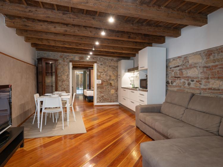 Living room with kitchen, brick wall and exposed beams at Hotel Touring Verona