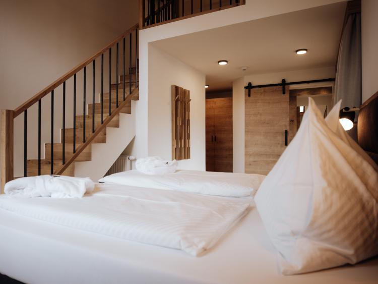 Schlafzimmer mit großem Bett und Treppe im Hotel Forstauerwirt