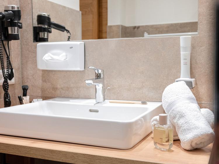 Waschbecken mit Föhn und Handtüchern im Bad des Hotel Forstauerwirt