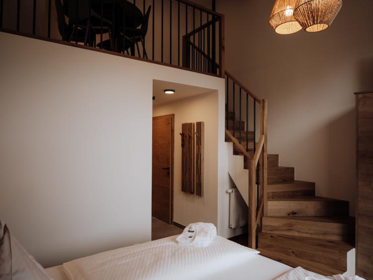 Schlafzimmer mit zwei Betten, Holztreppe und Hängeleuchten im Hotel Forstauerwirt