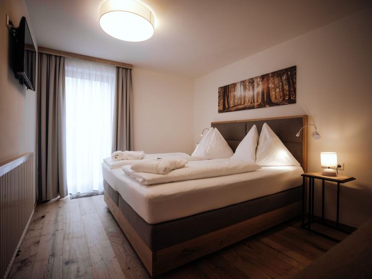 Schlafzimmer mit Doppelbett und Fenster im Hotel Forstauerwirt