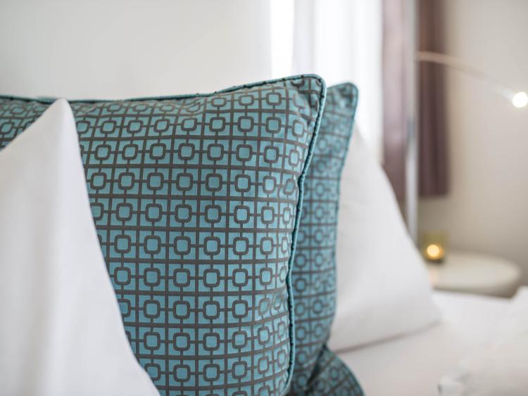 Kissen mit modernem Muster und Text auf einem eleganten Bett.