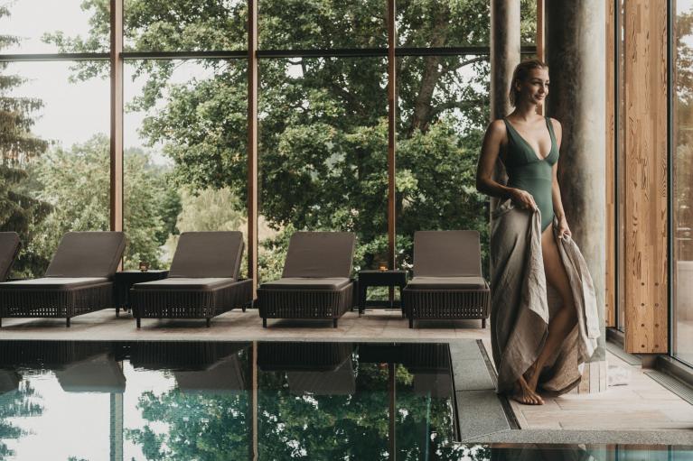 Frau am Pool mit Blick auf Bäume im Eibl-Brunner Spa-Bereich