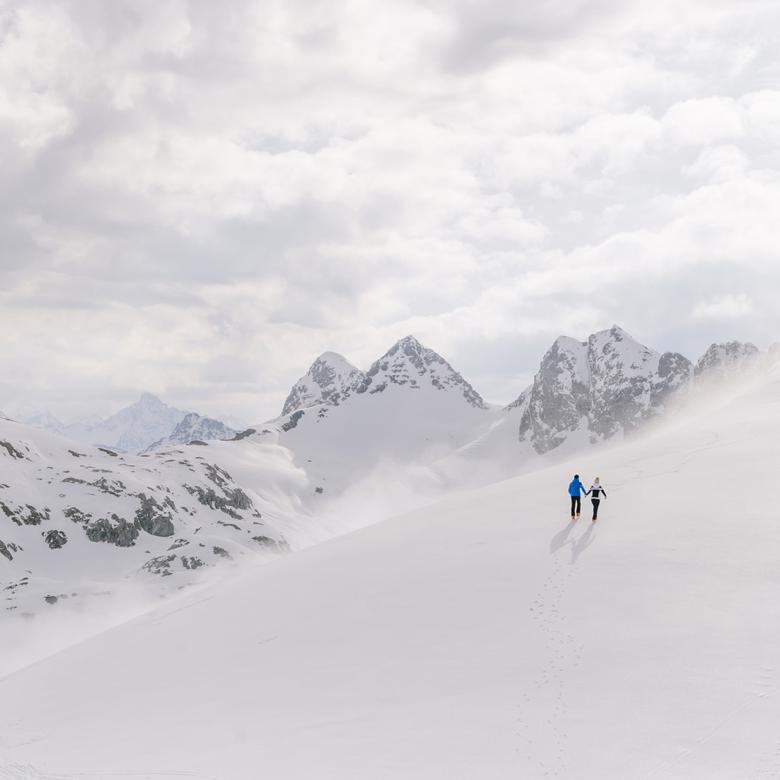 Zwei Personen wandern im Schnee mit Bergen im Hintergrund Hotel Aurora