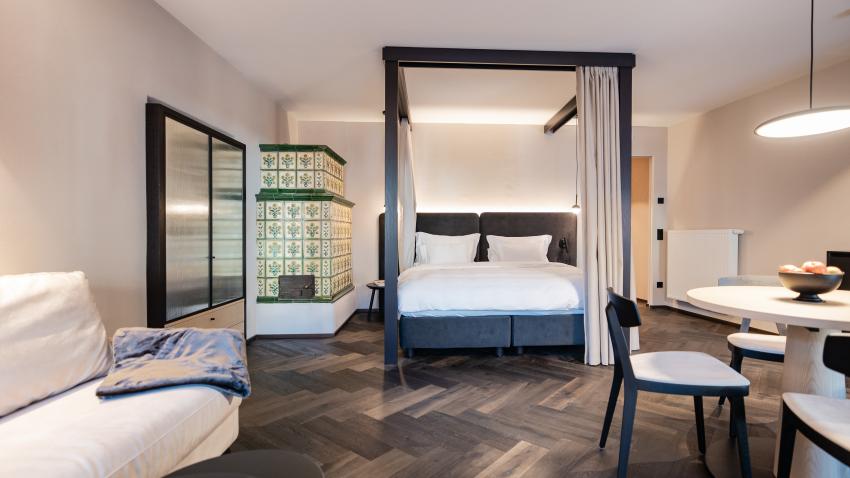 Schwarzer Adler hotel room with canopy bed and tiled stove