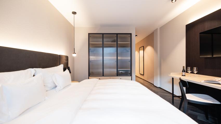 Modernes Hotelzimmer Schwarzer Adler mit großem Bett und Schreibtisch