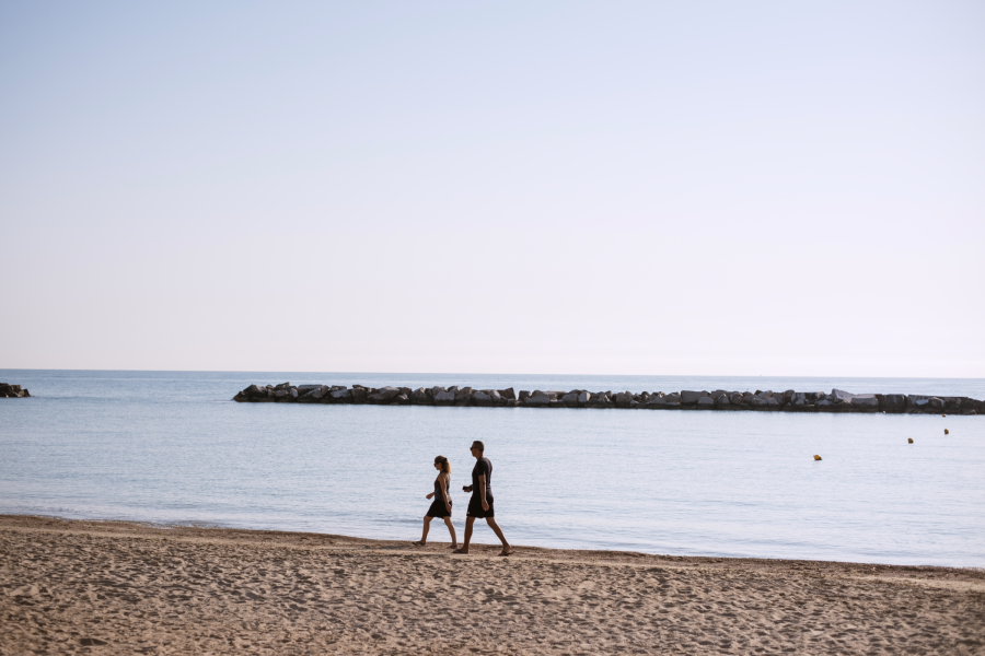 Two people walk along the beach at Natural Village Resort