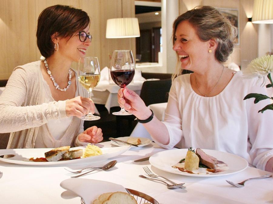 Zwei Frauen stoßen in Allgäu Sonne Restaurant beim Essen an