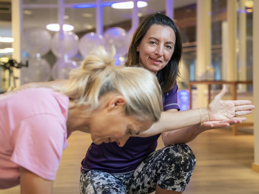 Sportlehrerin korrigiert Übung bei einer Frau